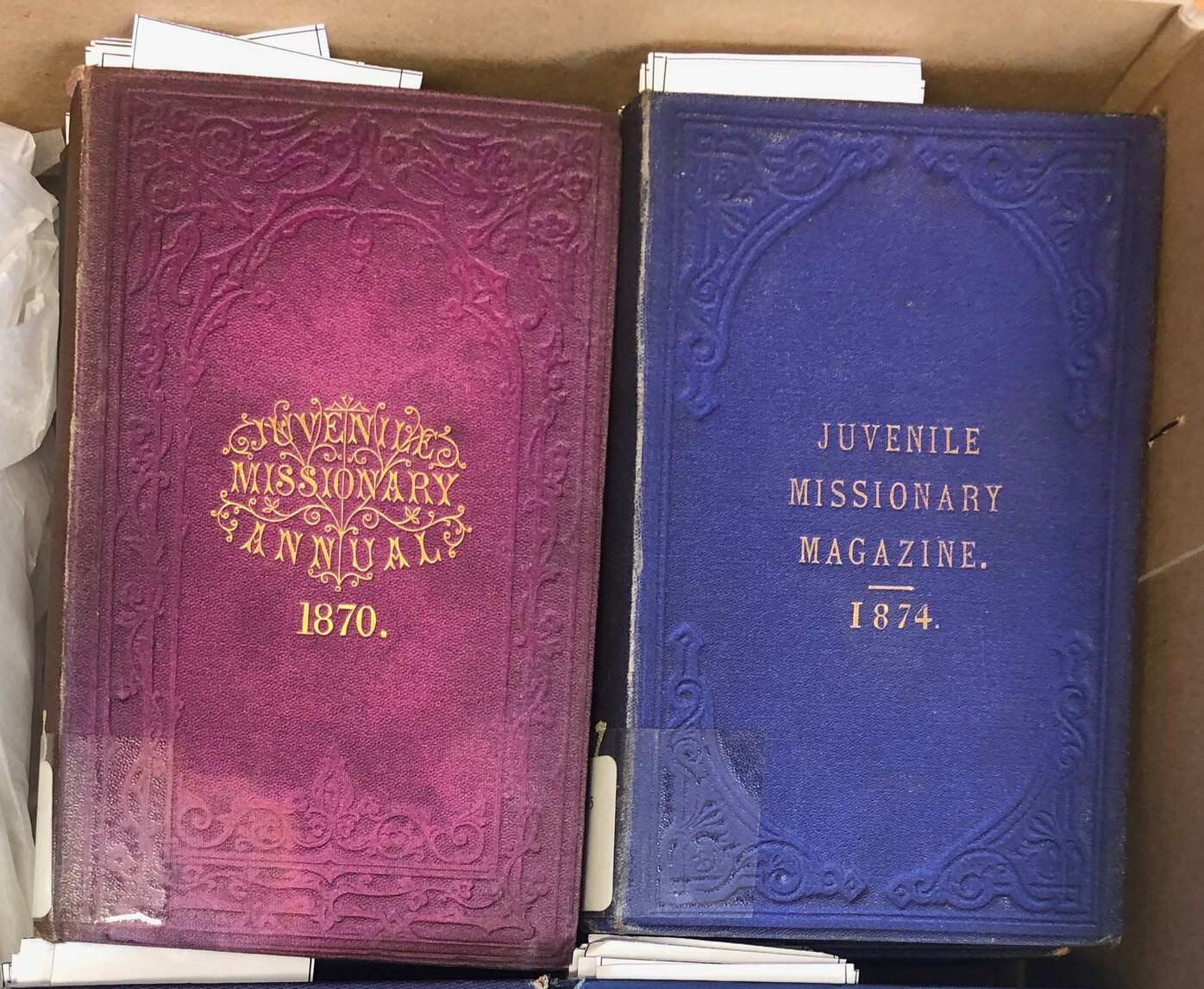 Volumes of Juvenile Missionary Annual (1870) and Juvenile Missionary Magazine (1874) side by side.