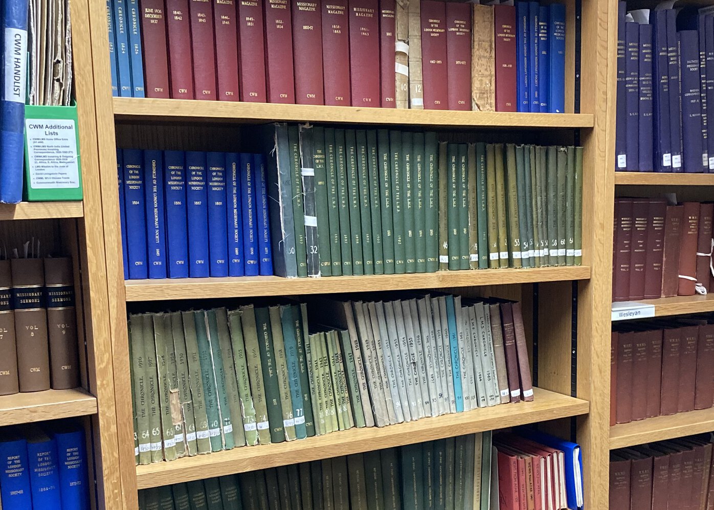 A series of bound volumes of varying colors on several bookshelves.