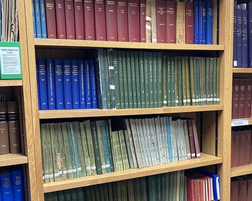 A series of bound volumes of varying colors on several bookshelves.