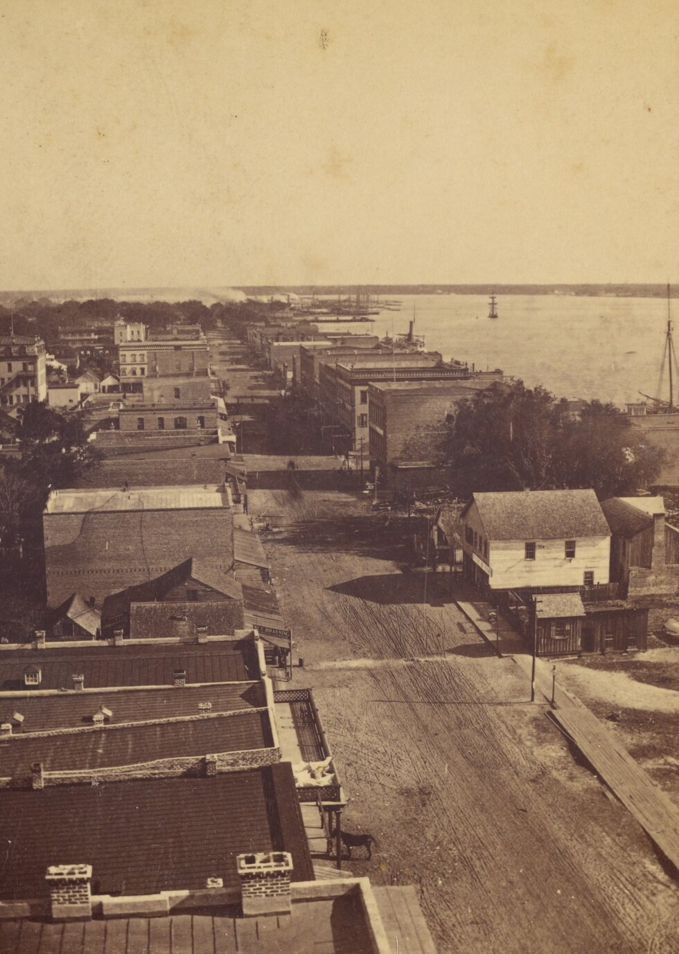 Bird's eye view of street, buildings on both sides, with a large waterway on one side.