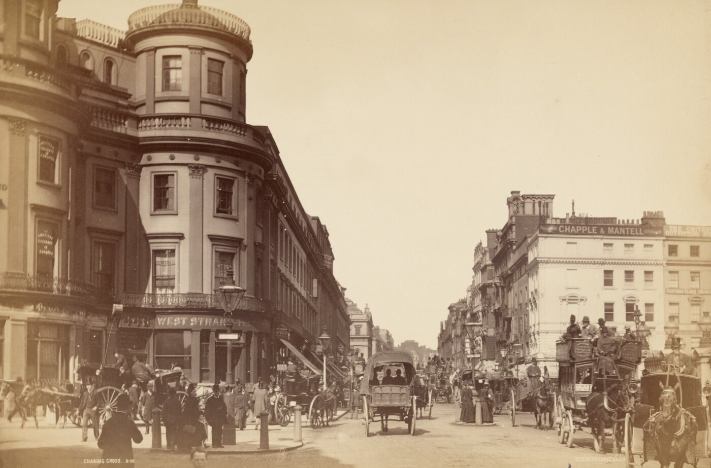 View looking down a street with buildings on both sides and horse-drawn carriages in the street.