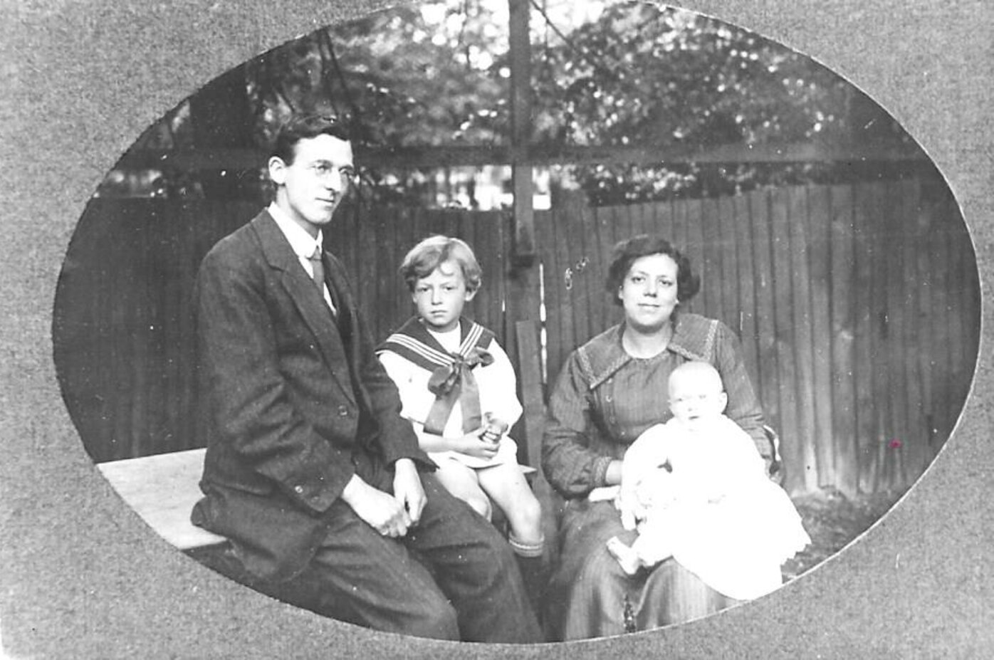 A man and woman sitting with two children; the woman holds a baby on her lap.