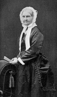 Portrait of a woman in a bonnet and dress standing and holding paper.