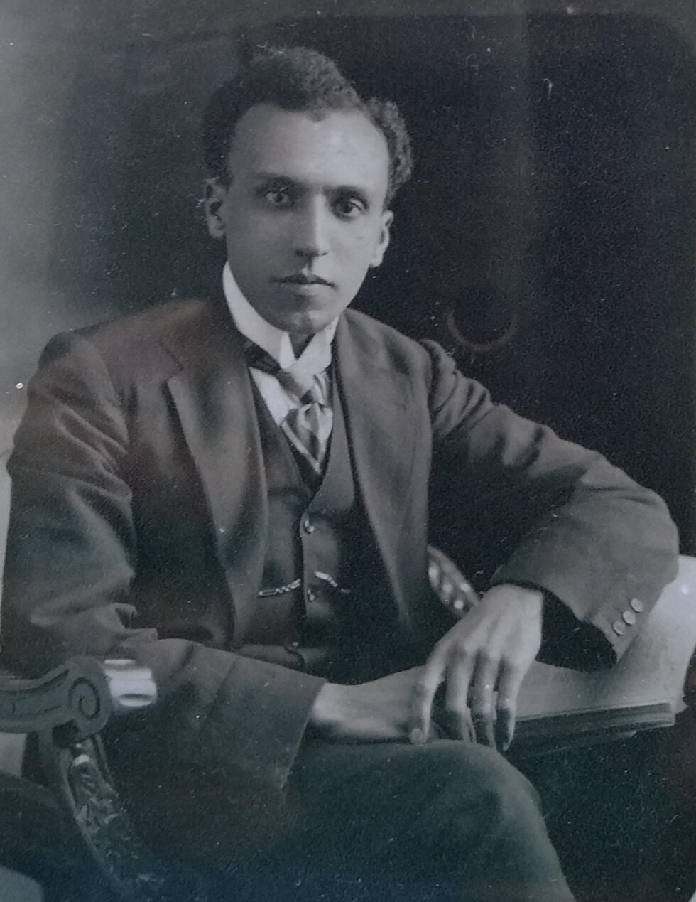 Portrait of a seated man in a suit, who looks at the camera.