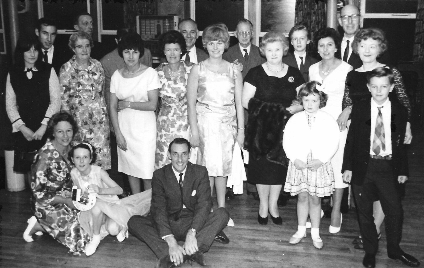 A photograph of a group of people (a family), some sitting and most standing.