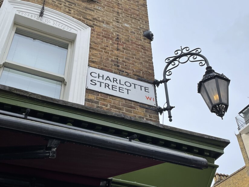 Street sign that reads ‘Charlotte Street‘ on a brick building with a street lamp.