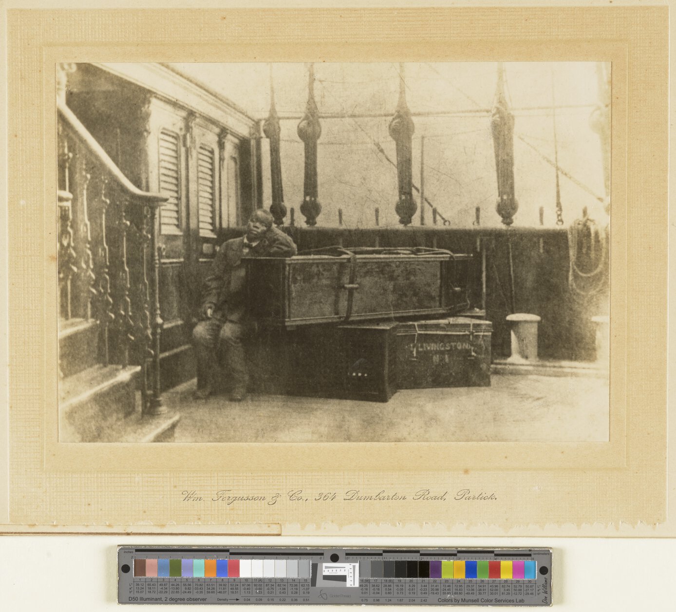 Jacob Wainwright seated on ship “Malwa,” leaning against David Livingstone’s coffin and other boxes.