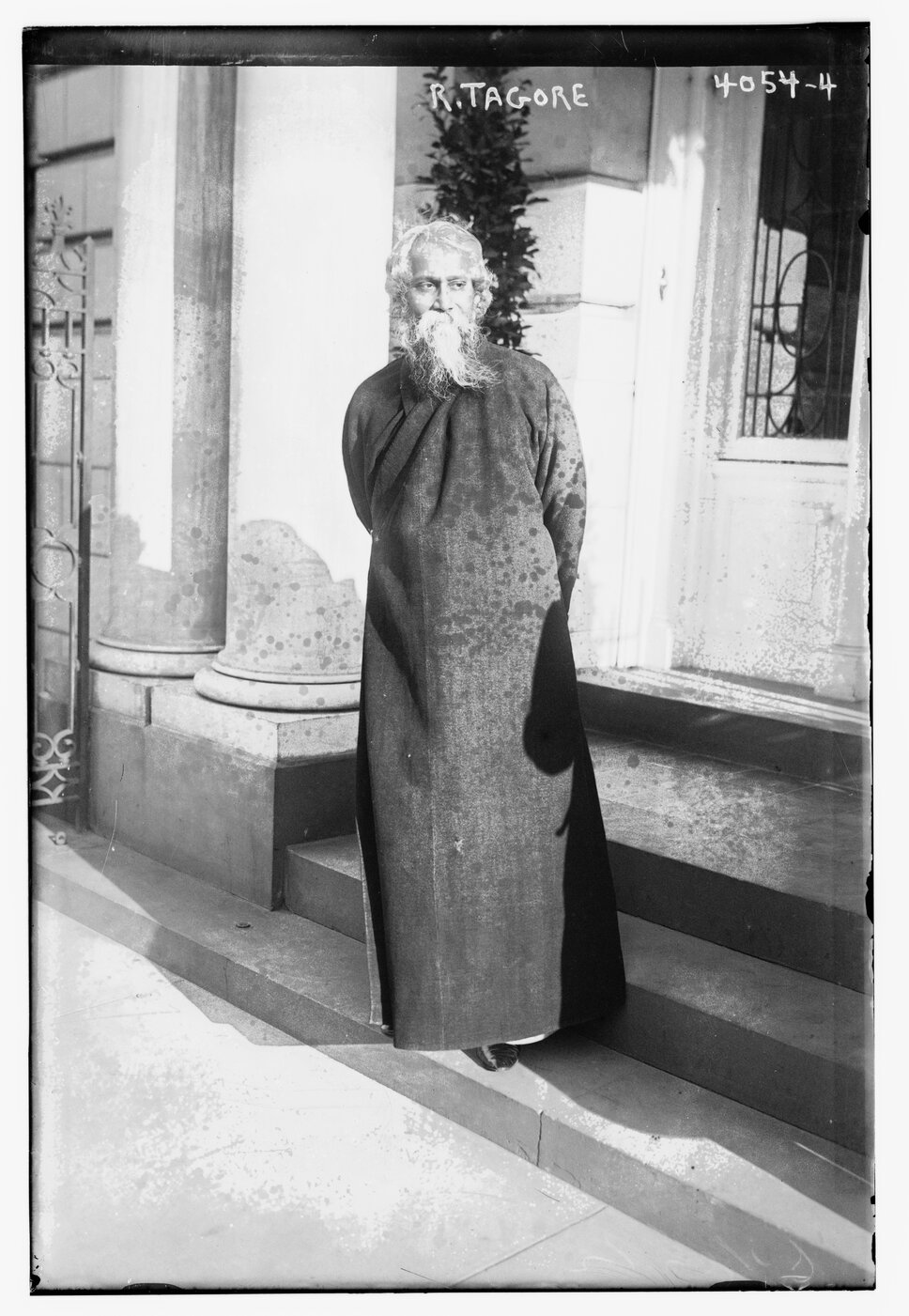Full-body portrait of Rabindarath Tagore, standing, facing forward, but looking to his left. 