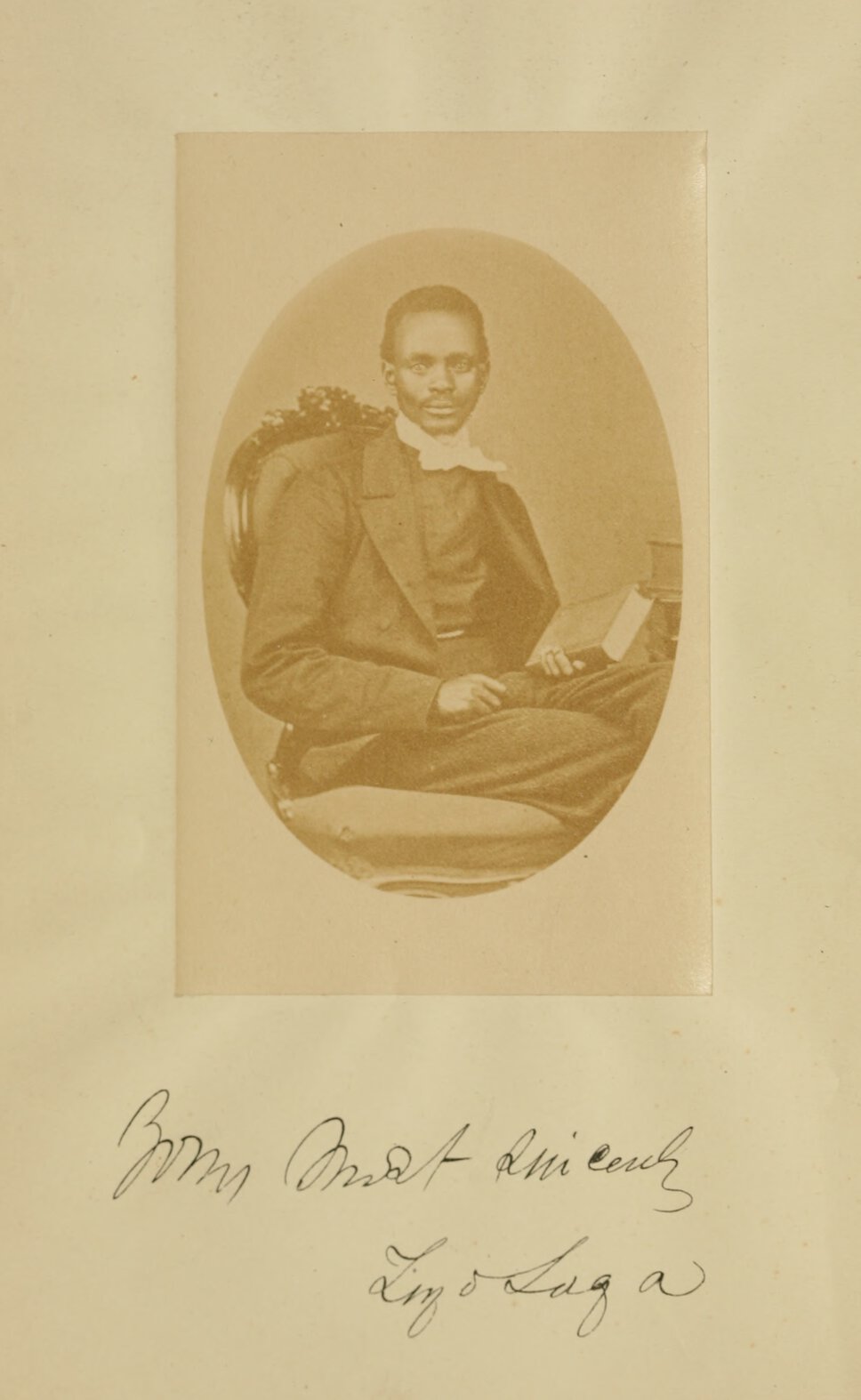 Tiyo Soga seat in quarter profile facing forward and holding a book.