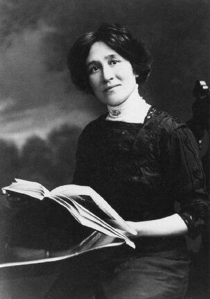 Edith Eaton seated in quarter profile, facing forward and holding a book.