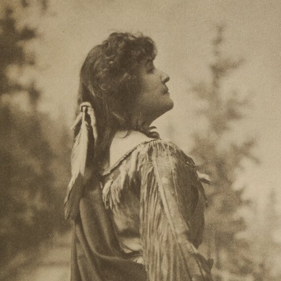 E. Pauline Johnson, standing with back to viewer, but with head in half profile to her right.