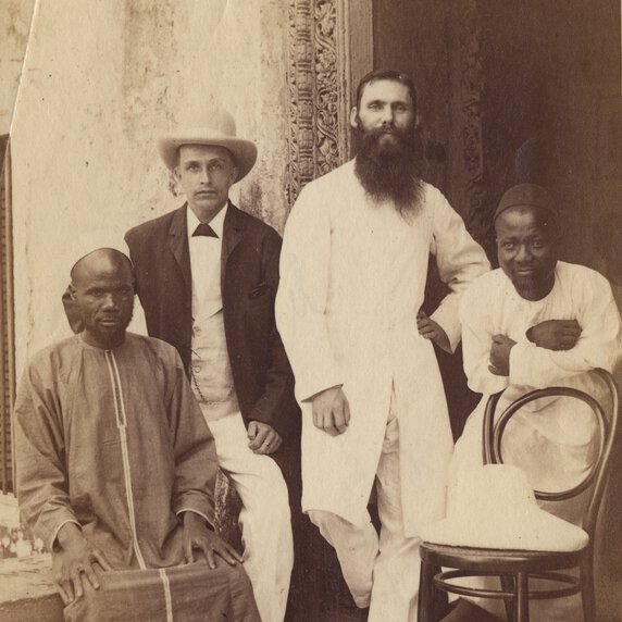 Abdullah Susi, Henry Charles Goodyear, [?] Gill, and Feragi posed near decorated doorway.