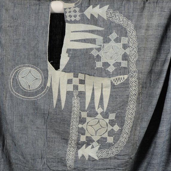 Gray robe with multiple embroidery designs at its center.