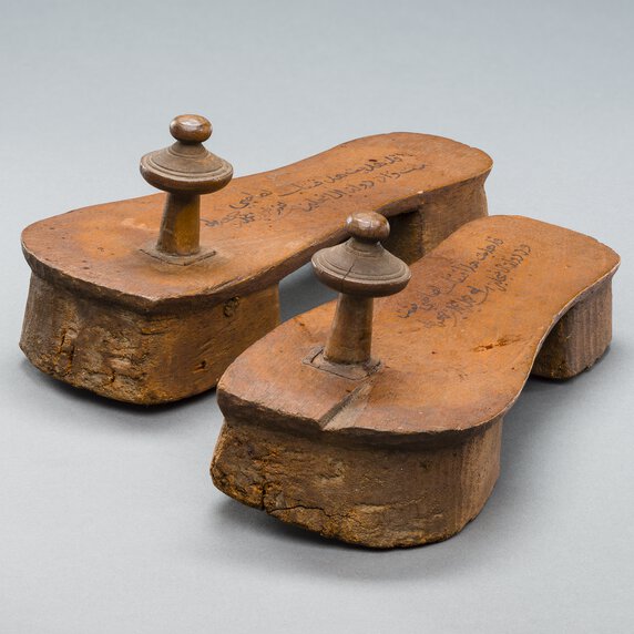 Tippu Tip's inscribed clogs side by side, rotated at 30 degree angle to viewer's right.