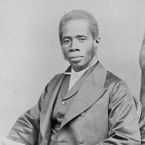 Edward Wilmot Blyden, seated, holding book, turned to his right, but facing forward.